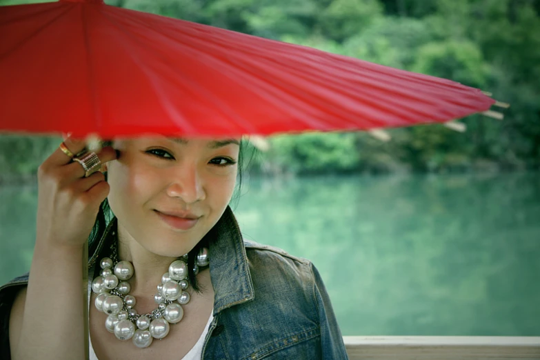 the woman wearing a pearl necklace is under an umbrella