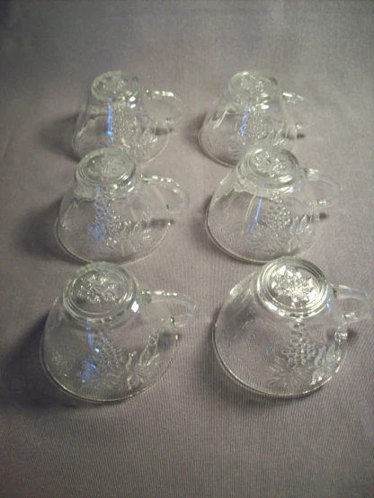 five glass tea pots are shown on top of a table