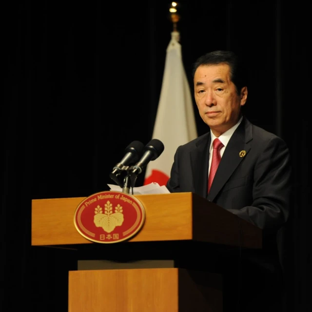 a man standing at a podium with microphones behind him