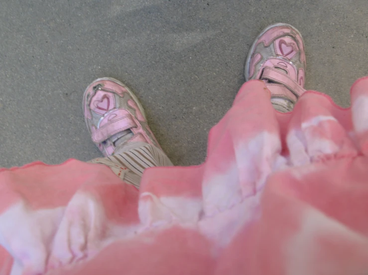 a girl's feet and pink shoes spread across a gray floor