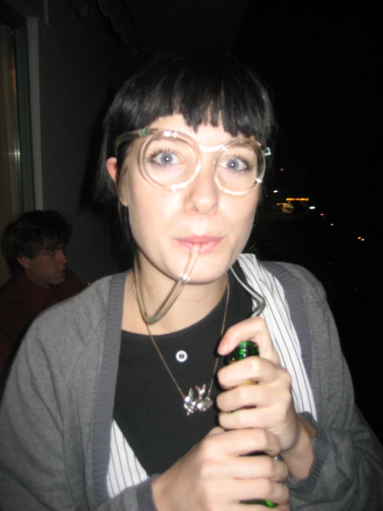 a girl with glasses is holding a small bottle