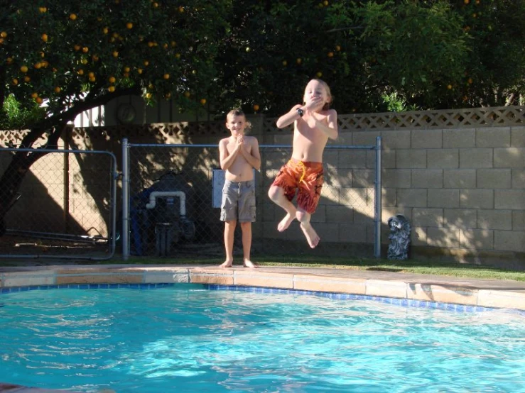 a boy jumping up in the air while another boy watches