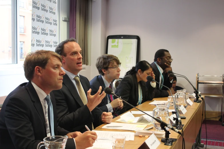 business people sitting at a table with microphones