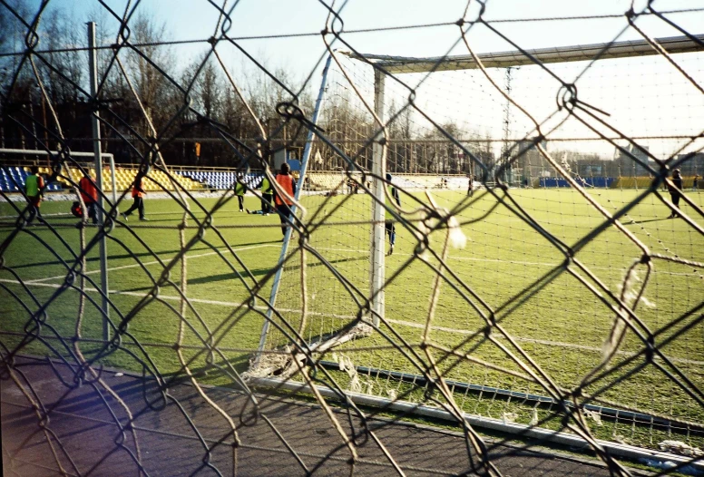 a soccer game behind a fence with players on it