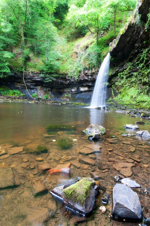 some rocks are under a stream and a waterfall