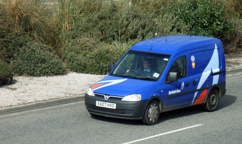a blue van with an arrow painted on it's side drives down a road