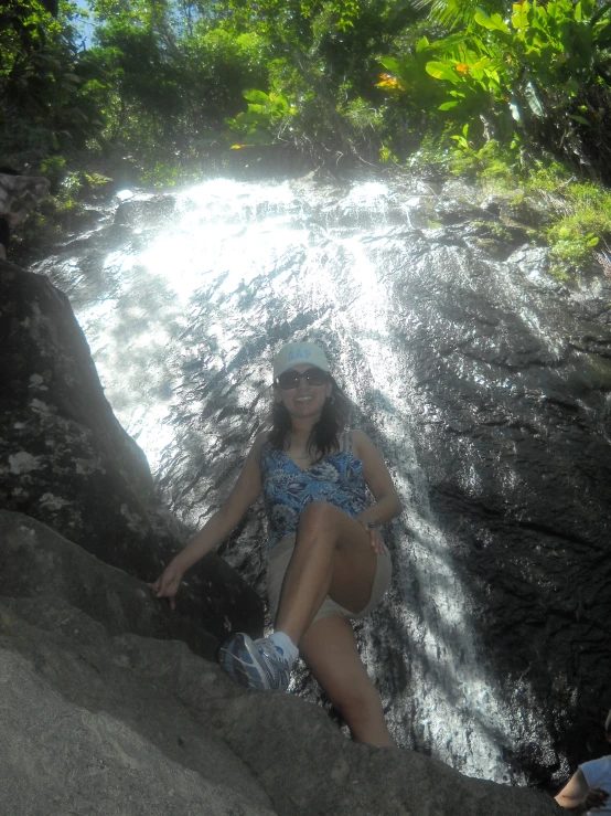 a woman is sitting on rocks in a stream