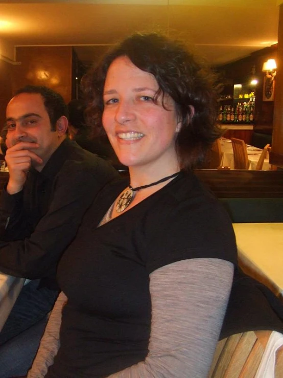 two people smiling at the camera at a restaurant