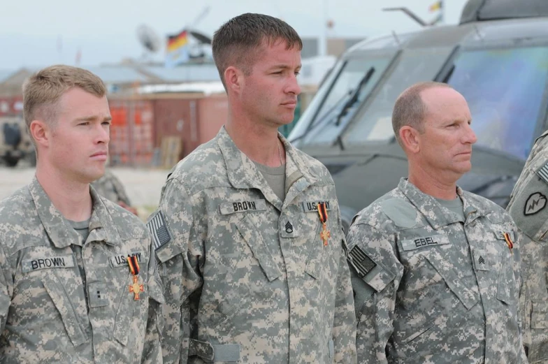 three men in uniform looking at soing