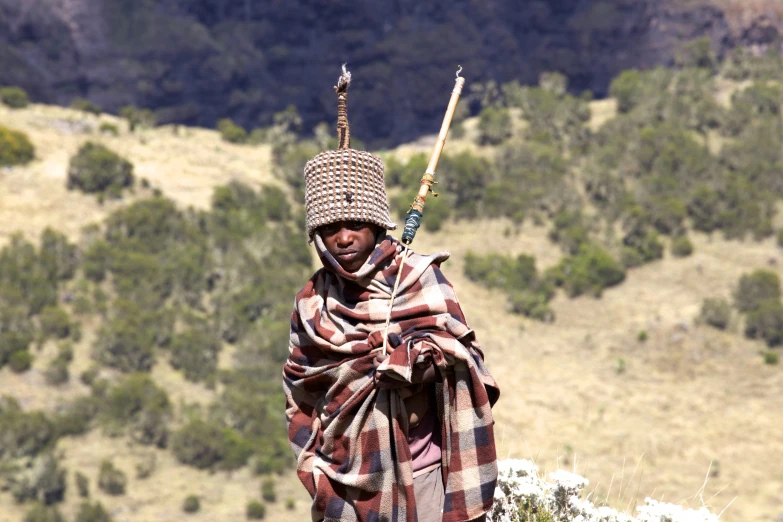 a person wearing an old headgear and holding a stick on a field