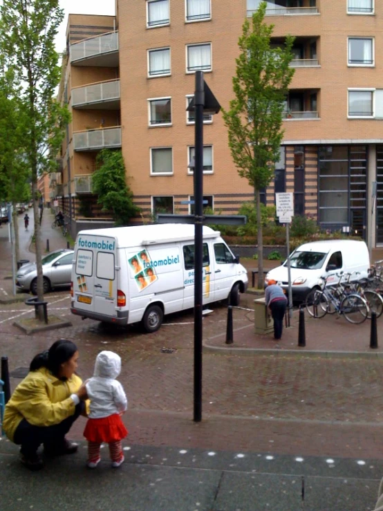 a woman with a child sitting on the ground near a curb