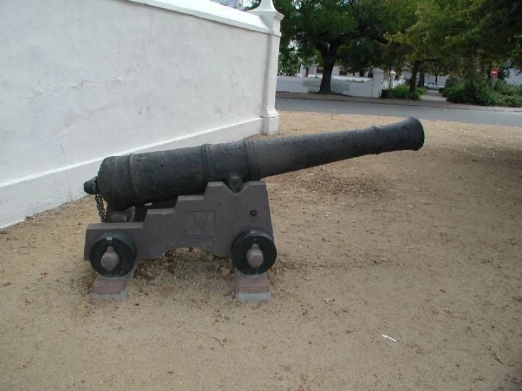 the cannon stands on two small wheels outside a building