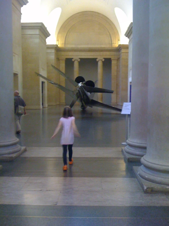 the small girl in the pink sweater is walking through the marble floor