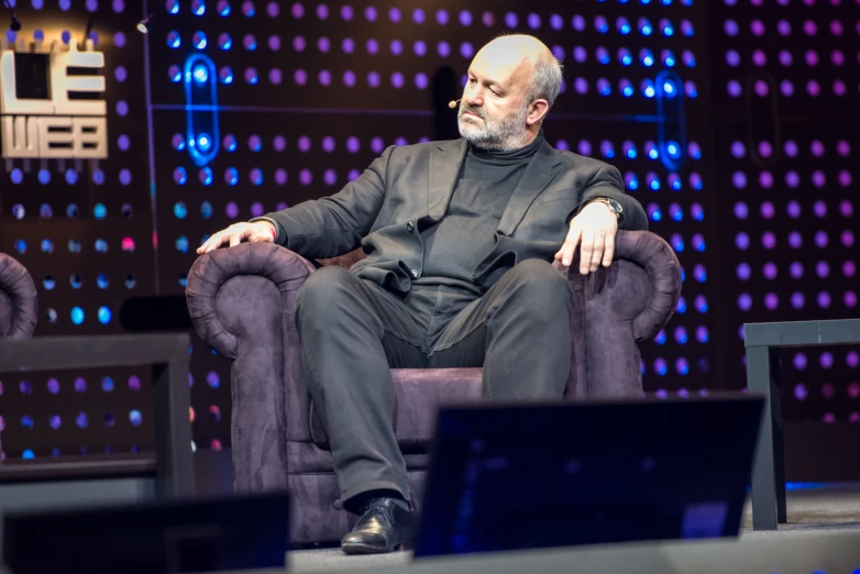 a man sitting in a chair in front of a wall with dots