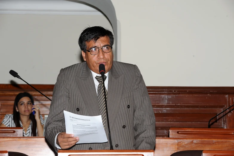 the man in a suit is standing at the podium with a microphone in his hand