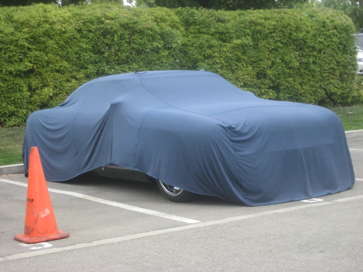 a car covered with blue fabric parked in a parking lot