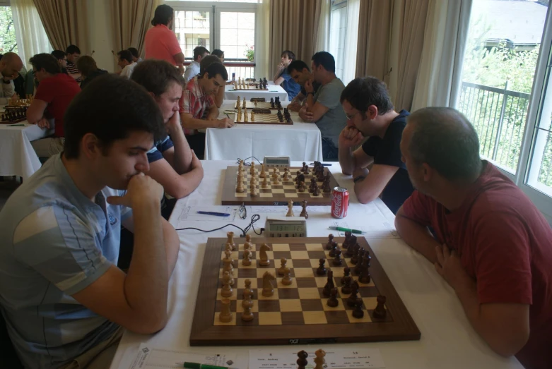 several people play chess on a long table