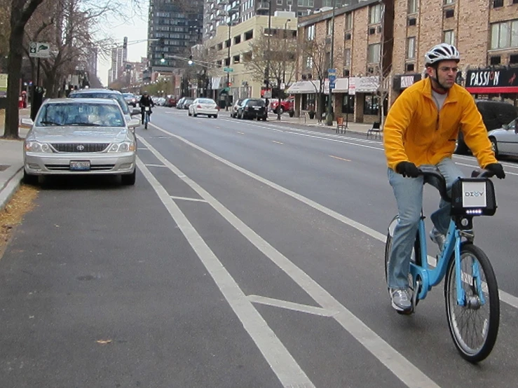 man with helmet on riding bicycle in middle of roadway