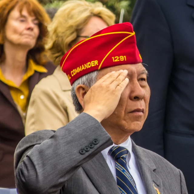 an elderly man wearing a hat and suit standing in front of other people