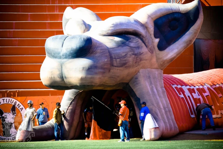 an elephant statue sitting on top of a field near people