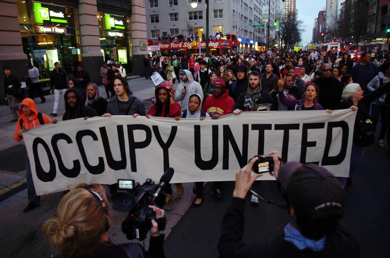 many people stand together holding a occupy united banner
