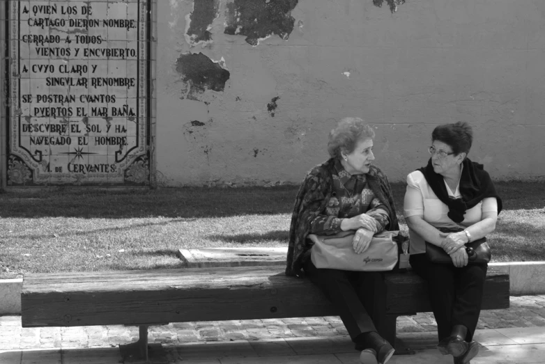a woman sits on a bench while another woman looks away from her