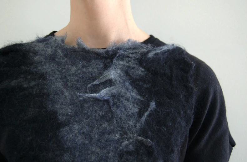 a man's dark shirt that is slightly untidy with a cat hanging off the side