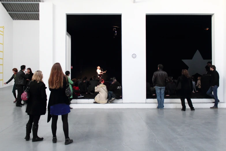 a group of people gathered in an art museum looking at the artwork