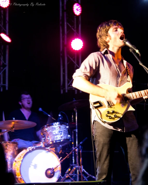 a man standing on stage while playing a guitar