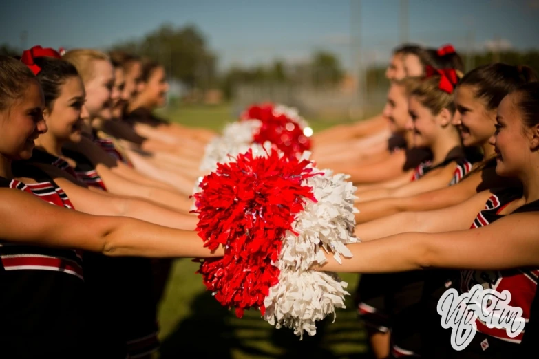 cheerleaders in red and white costumes stretch their hands