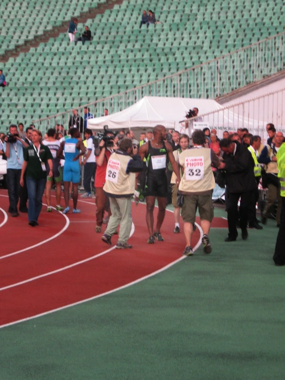 a group of runners running down a race track with their signs