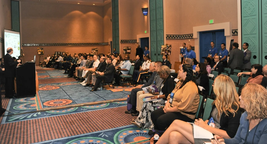 people sit in chairs at the front of a room speaking