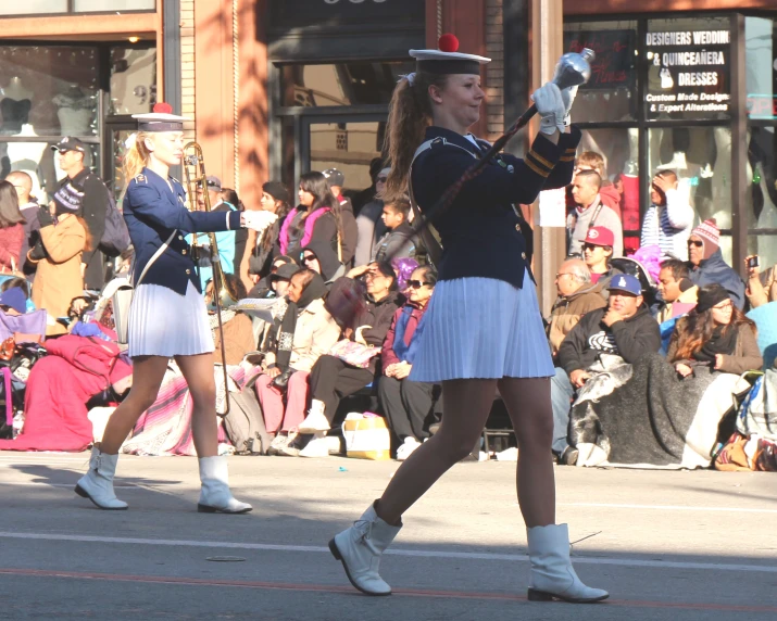 young women are playing instruments in front of people on the street