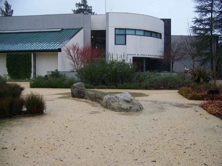 a white building with large green roof next to a rock