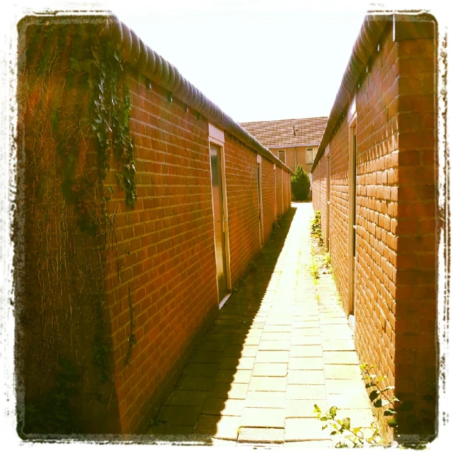 a long walkway lined with brick walls with a light in the middle