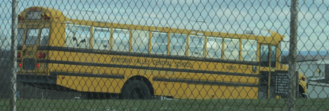 a close up of a school bus behind a chain link fence