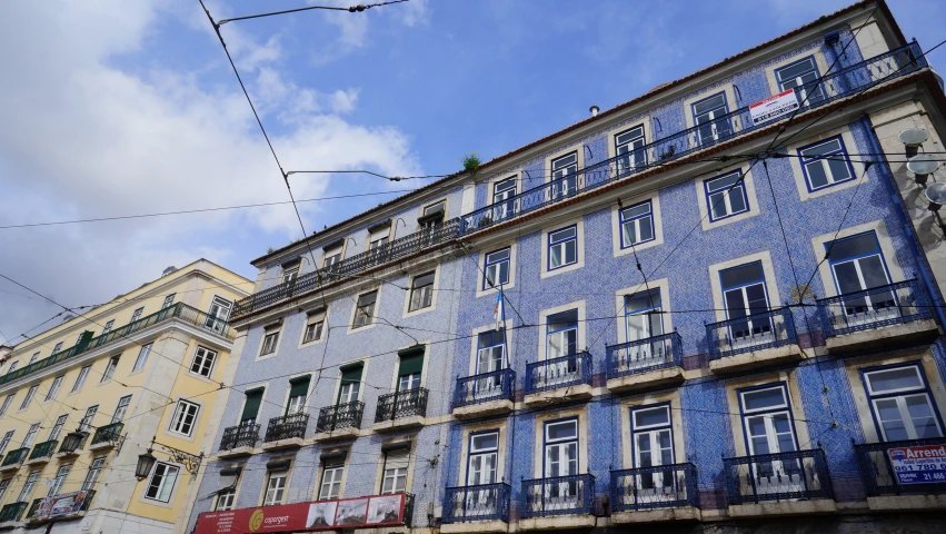 two buildings with blue painted balconies and yellow building with a balcony