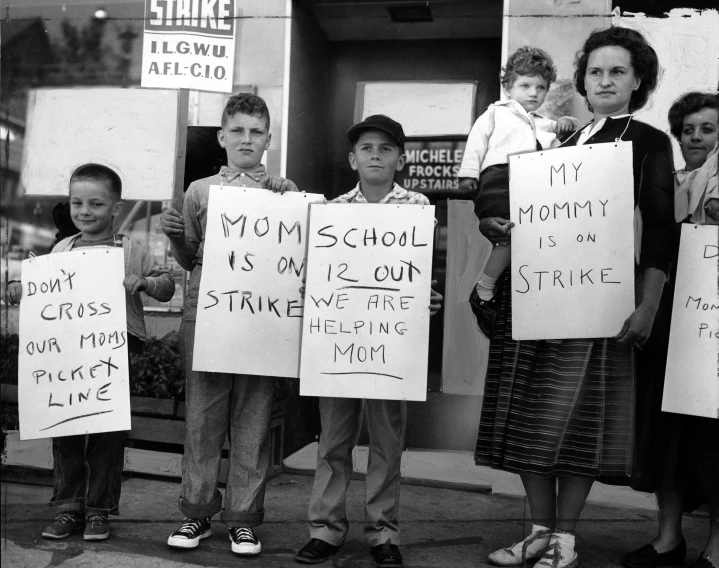 a group of people holding signs standing in front of a store