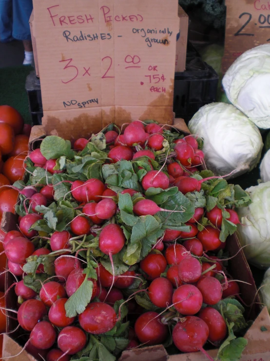 vegetables sit in the box to be sold at an outdoor market