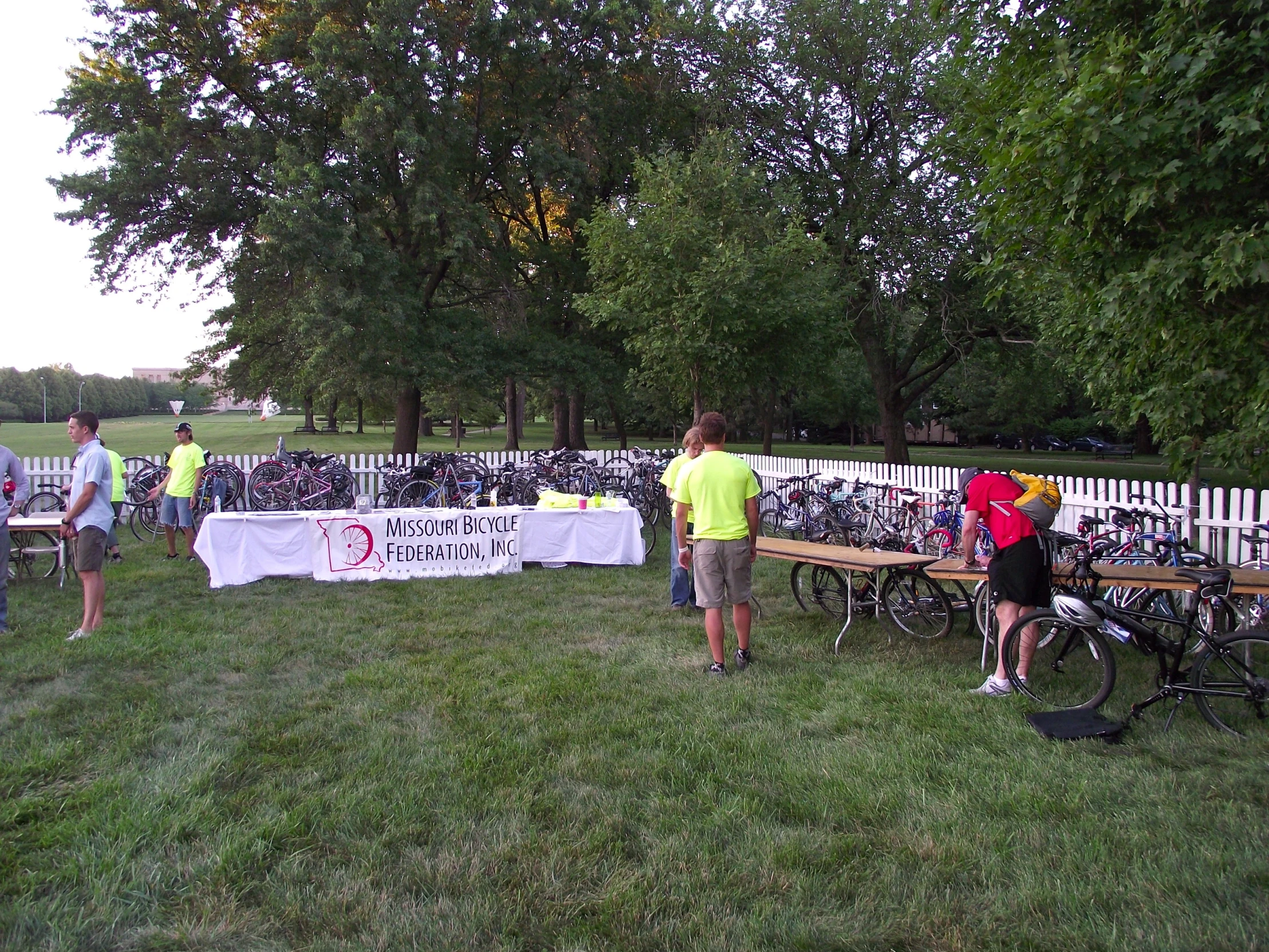 people in yellow shirts are sitting at a picnic table near bikes