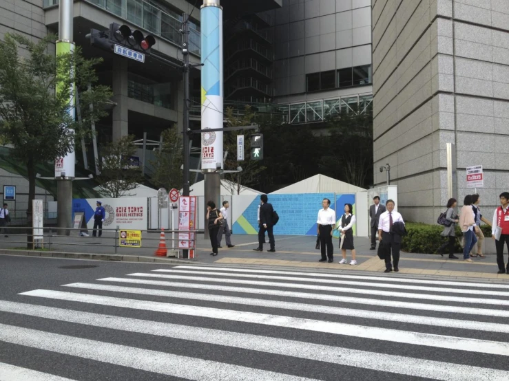 several pedestrians crossing the street in front of a tall building