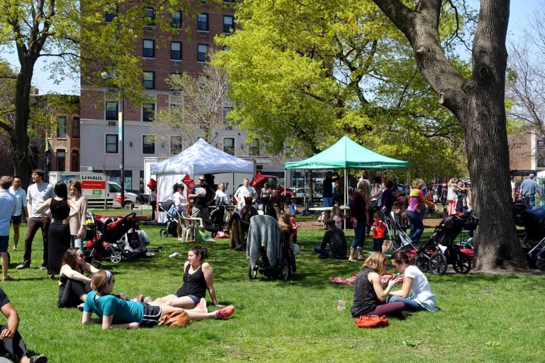 several people laying down in the grass with picnic tables and tents