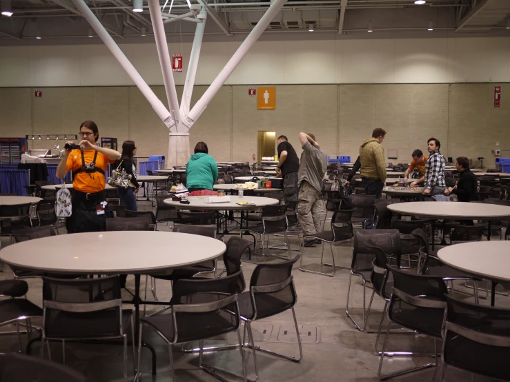 a room that has many tables and chairs with people working on computers