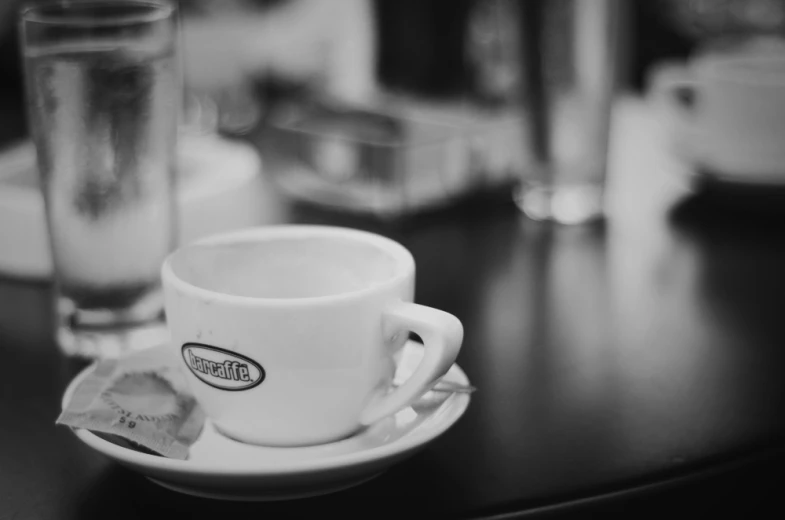 a cup of coffee sits on a saucer next to a glass of water