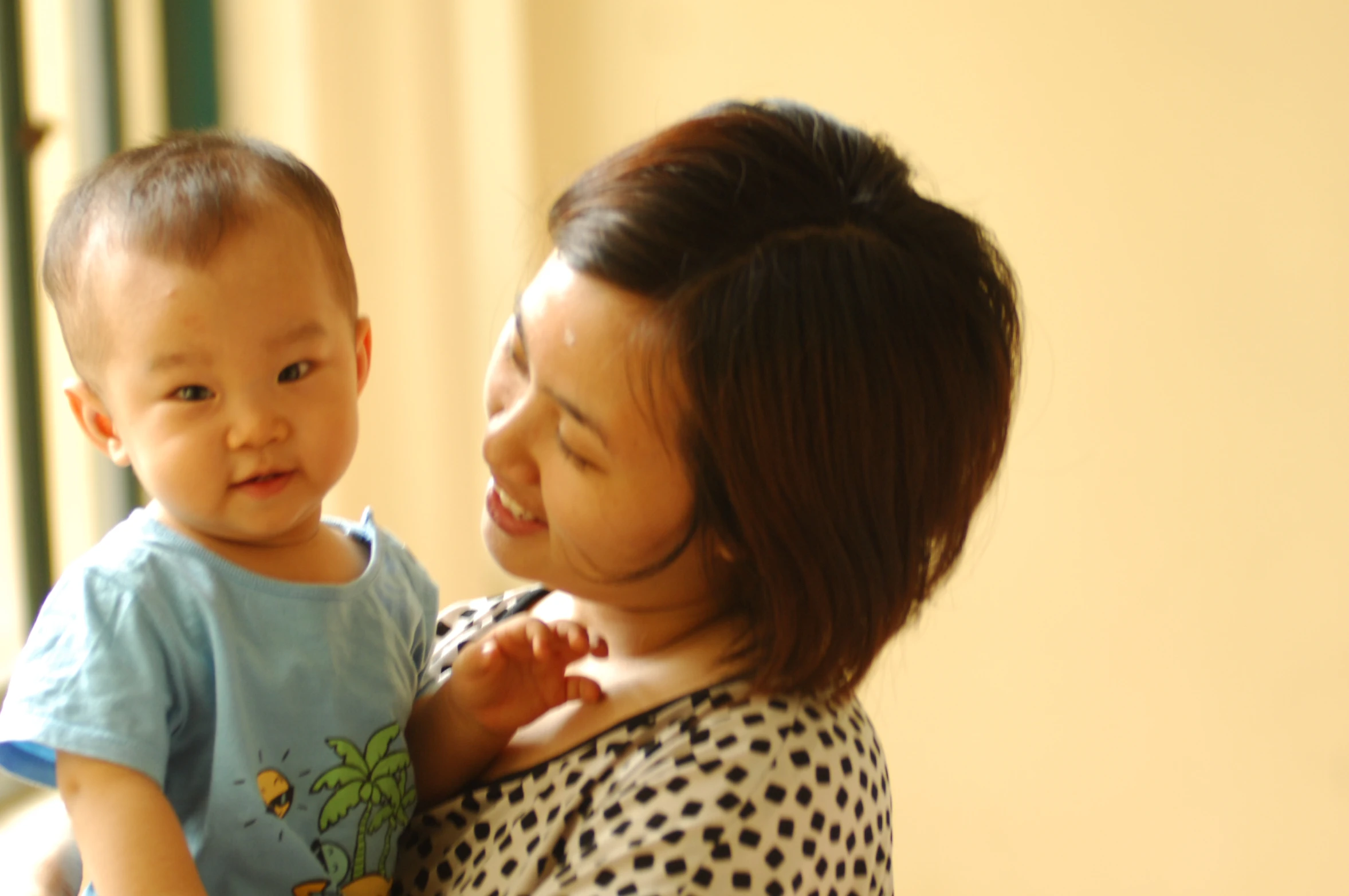 a little boy holding onto his mother in the room