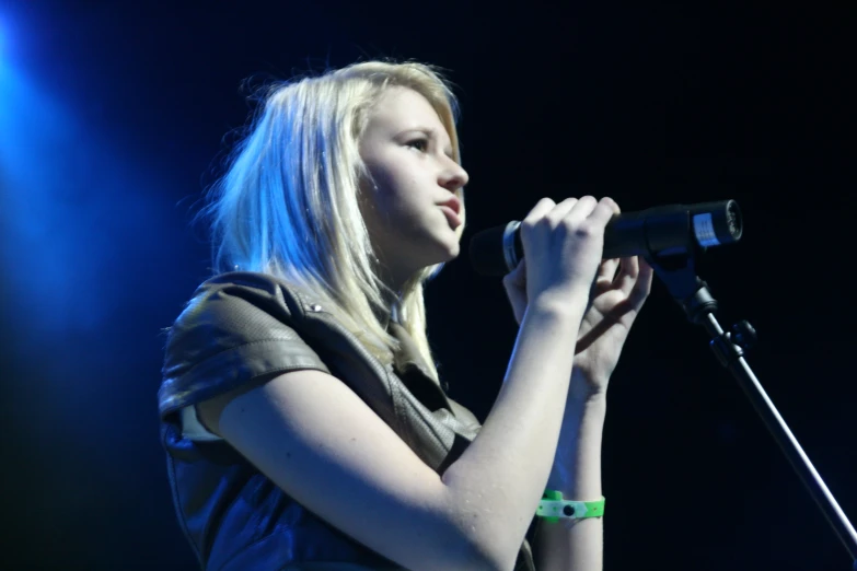 a young blond woman in front of a microphone on stage