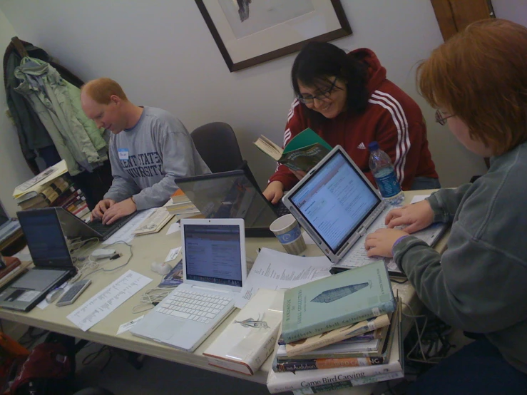 a group of people at a table with laptops