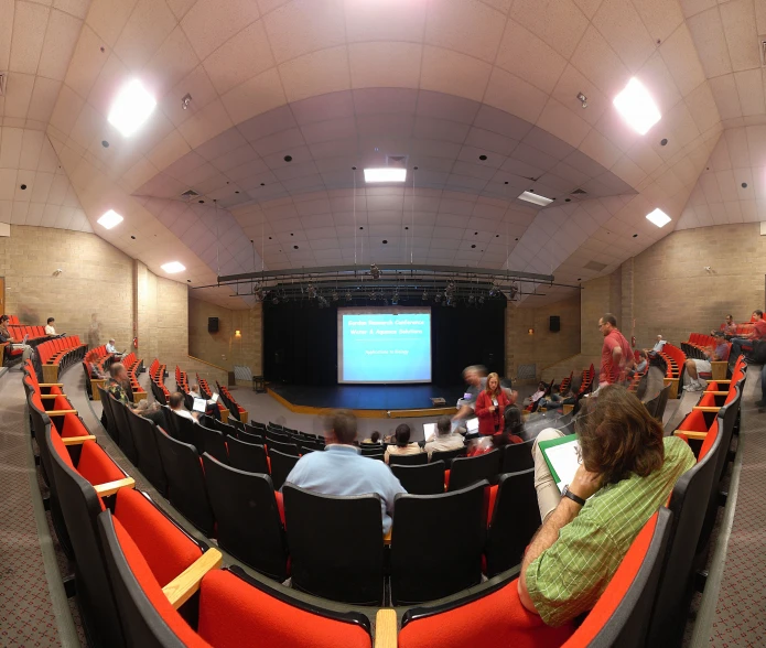 people are sitting in front of a lecture screen in the auditorium