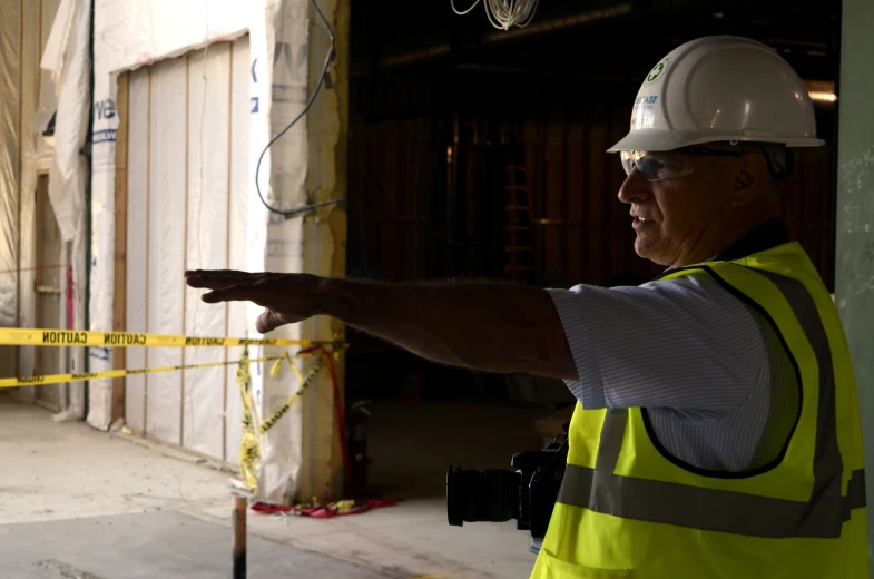 a man in safety gear pointing at a wall