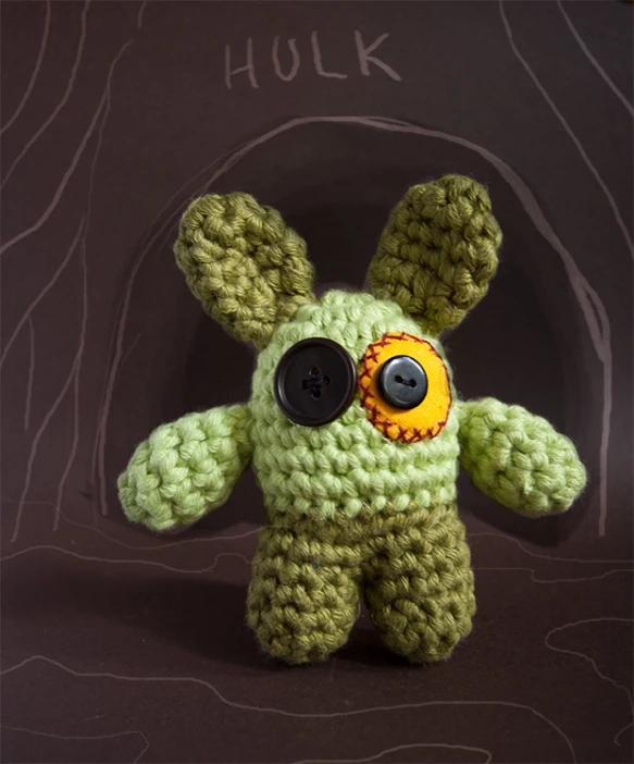a crocheted animal is posed on a dark surface